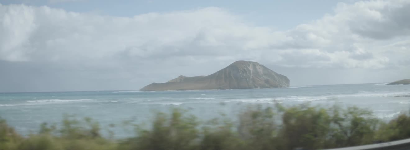 Ocean waves crest and break near a rocky island