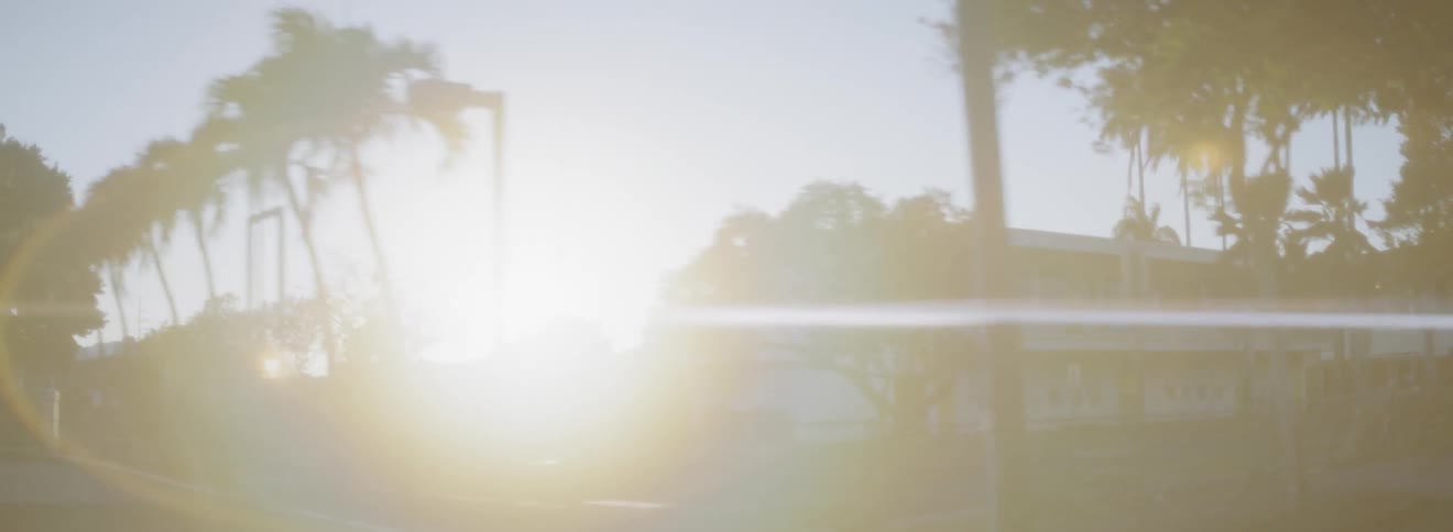 Sun setting behind buildings in a tropical city area