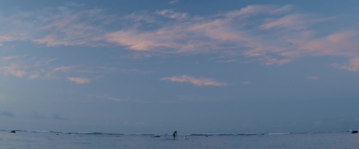A person rides a paddle board at sunset