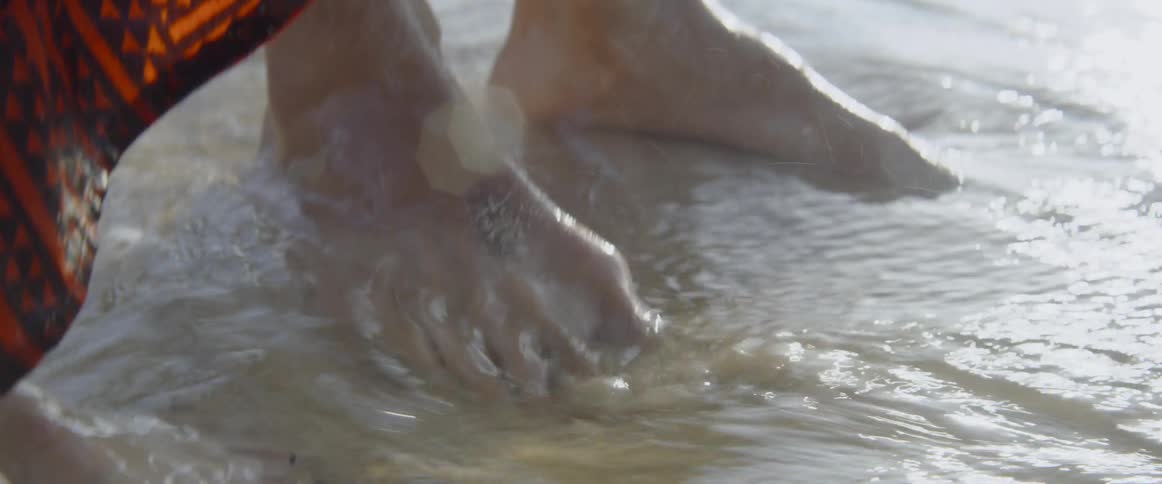 Oceans water washes over the feet of a man and a woman