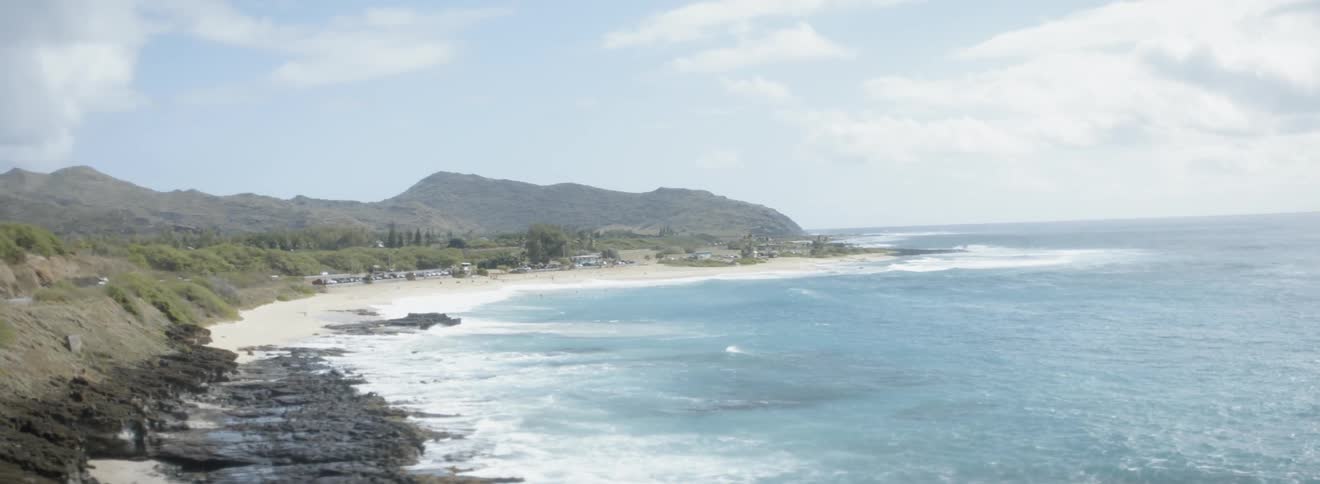 Vehicles are driving on a coastal highway near a beach during the day