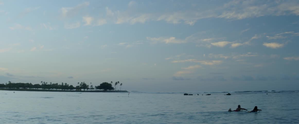 People paddle out into the ocean on their surfboards