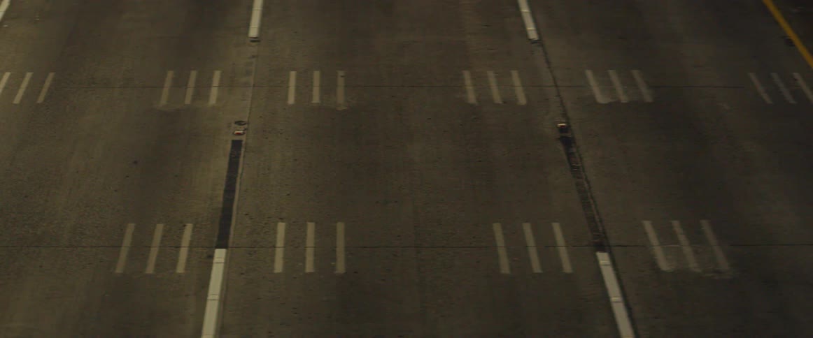 Vehicles are driving over a city street at night