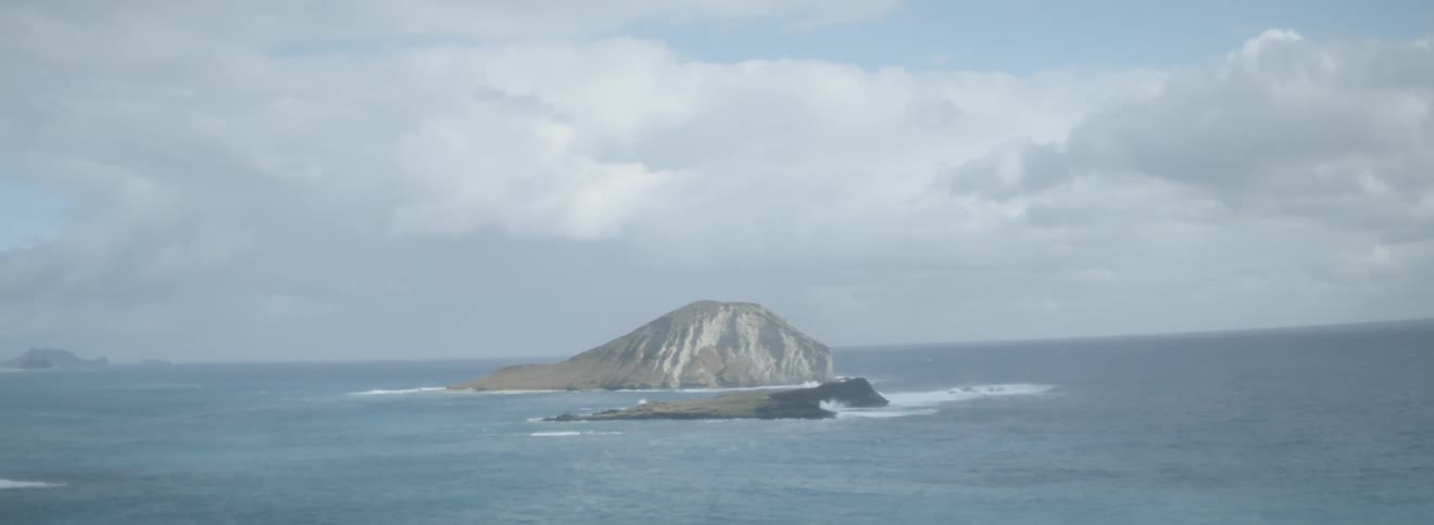 Ocean waves splash against small rock islands