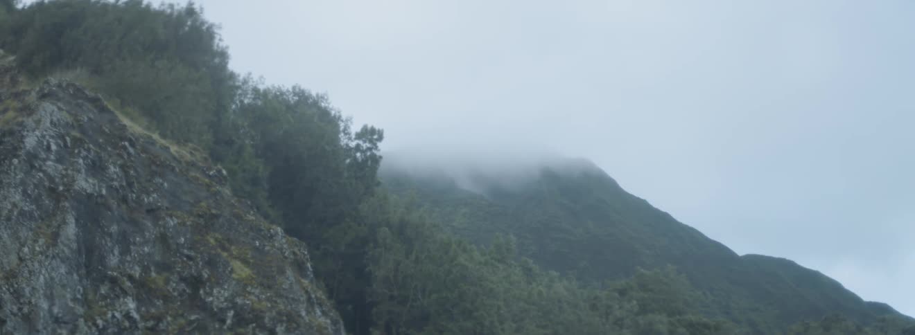 Fog and clouds are drifting over a mountain during the day