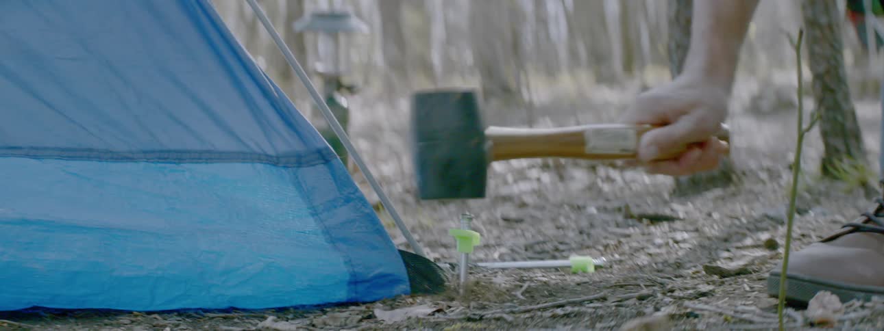 Person hammers a spike into the corner of a tent
