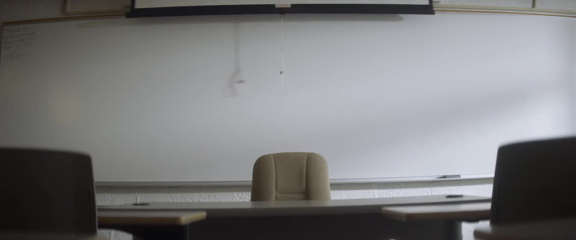 The projection screen cord casts a shadow in an empty classroom