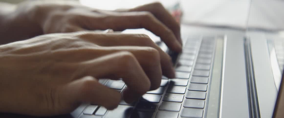 A man is typing on a laptop keyboard
