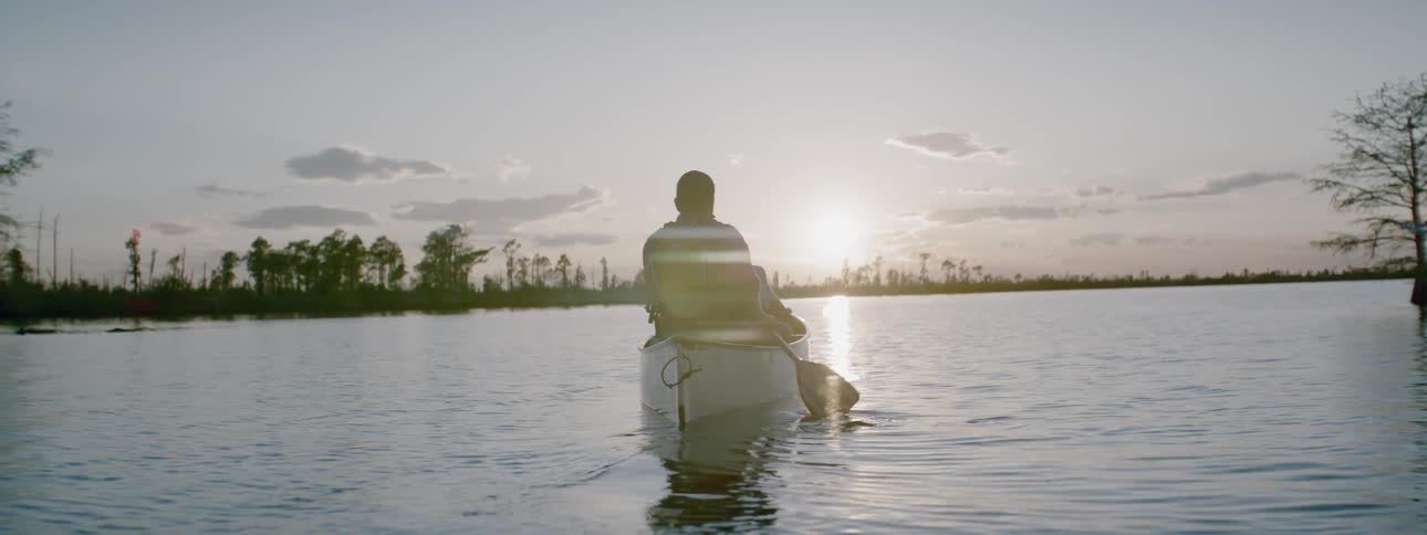Man with child rowing some calm waters near sunset