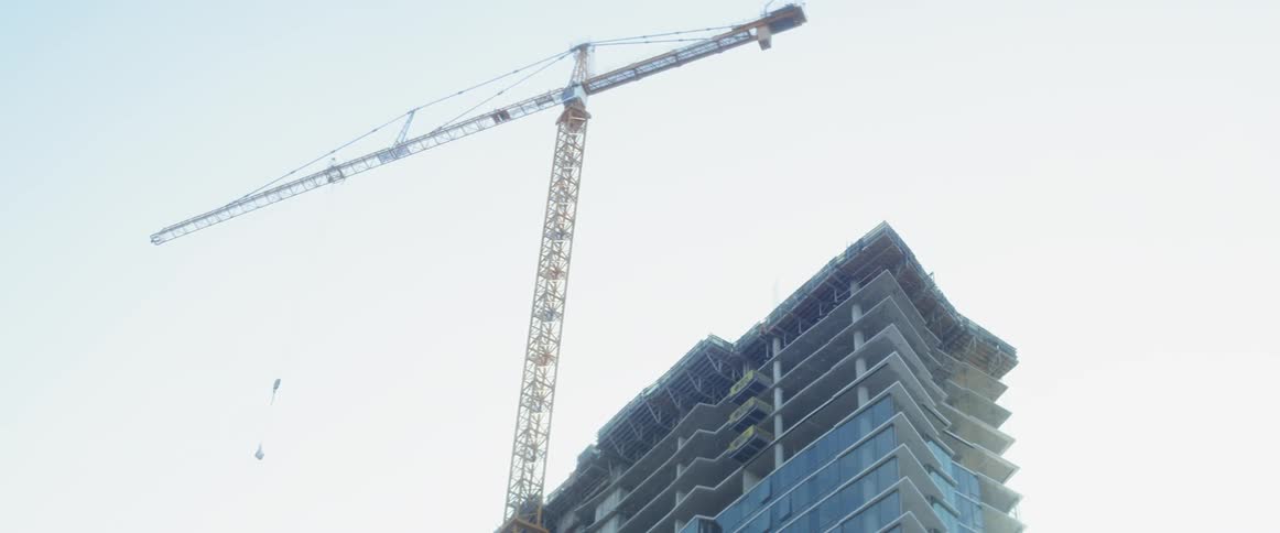 A construction crane rotates above a building