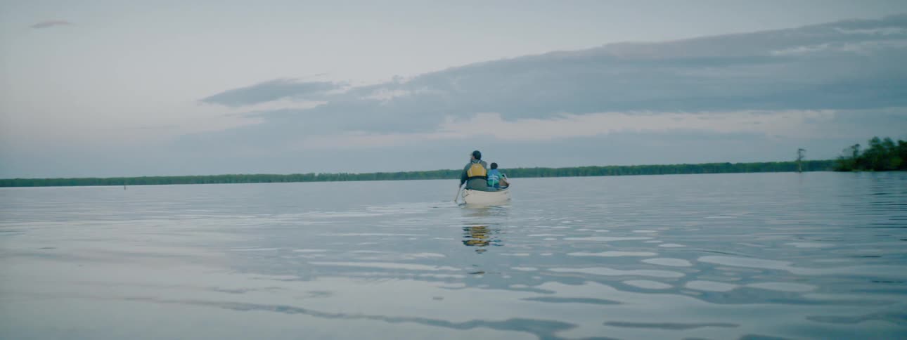 A man rows a boat with his child in it