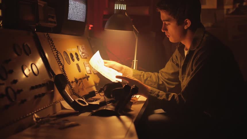 Man sits at a control tower reading a paper
