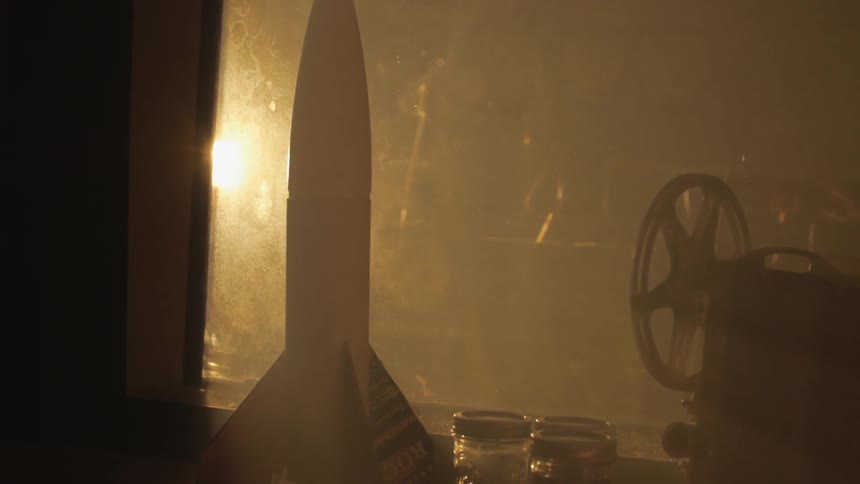 Toy rocket on a shelf near some jars in a dark room
