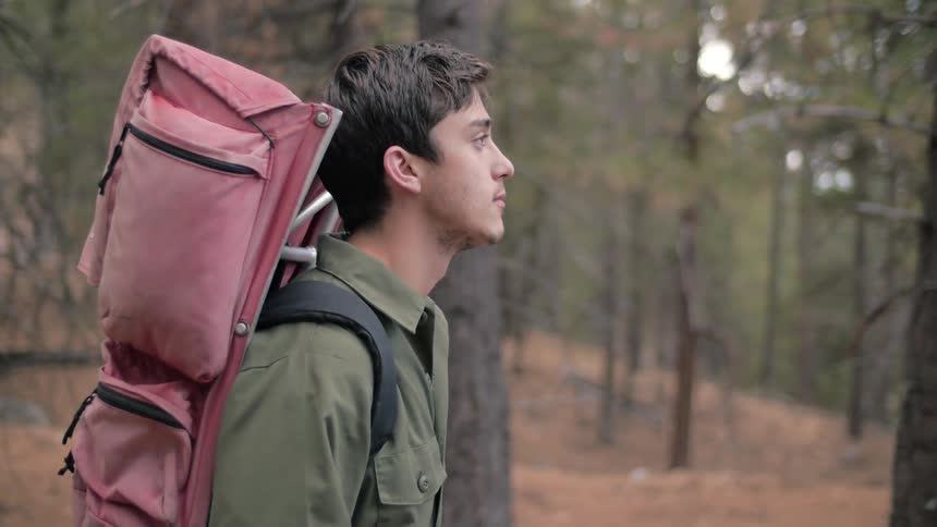 Man wearing a backpack walks through the forest