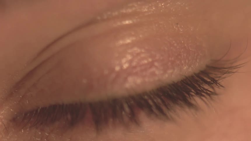 A person's closed eye opens and then squints