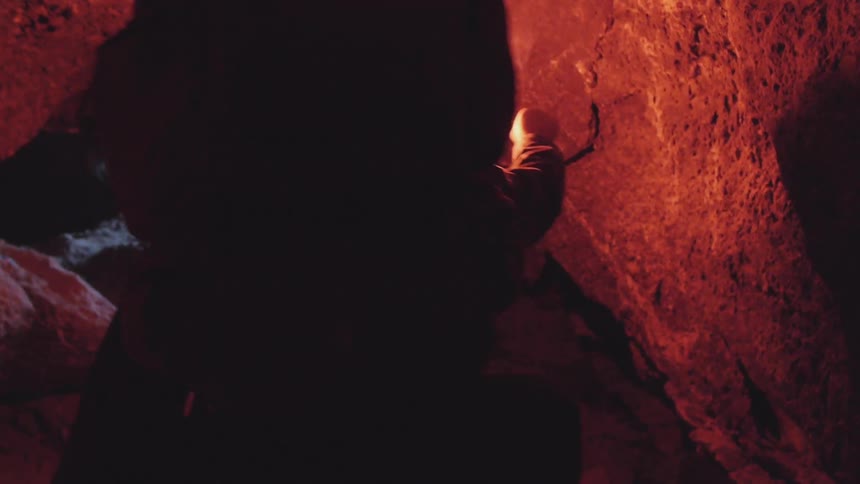 Man traveling to an exit of a cavern using a flare for light