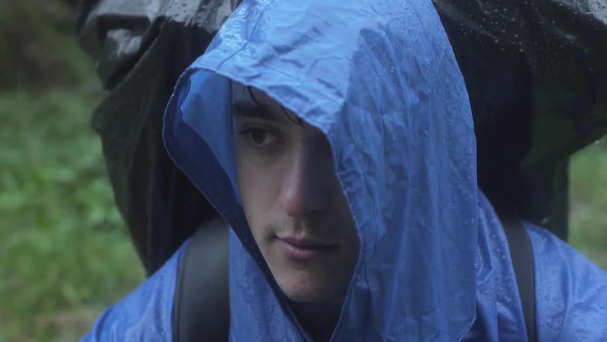Hiker stands in the rain by a forest