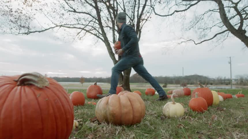 Man and woman run through a pumpkin patch