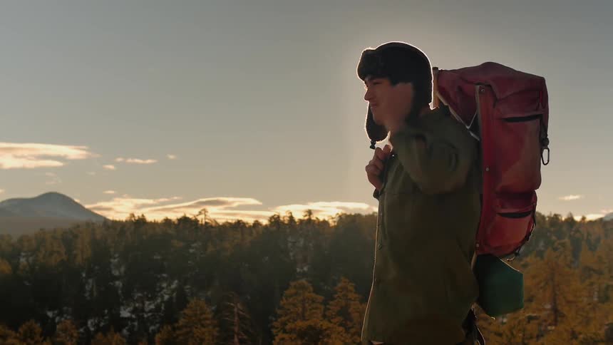 A man puts a hat on in a field