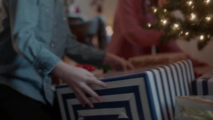 A girl and boy are checking out the presents under a christmas tree
