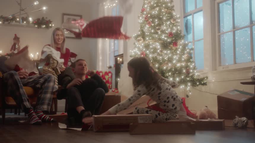 A family opens gifts next to a christmas tree
