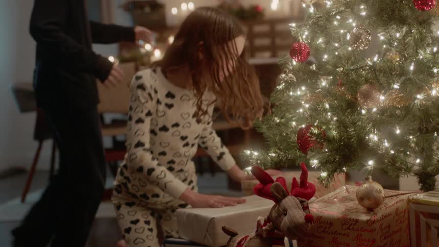 Brother and sister run to the christmas tree to open presents
