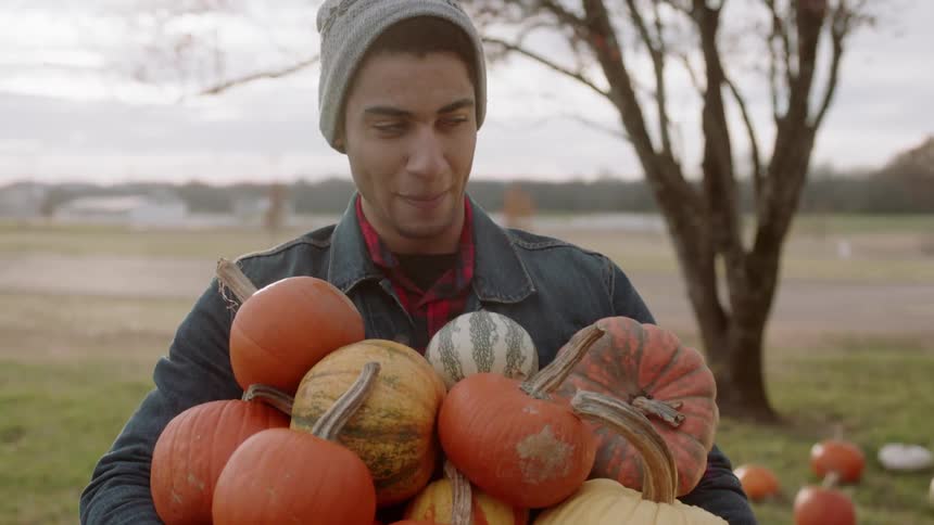 A woman stacks one more pumpkin into a man's full arms