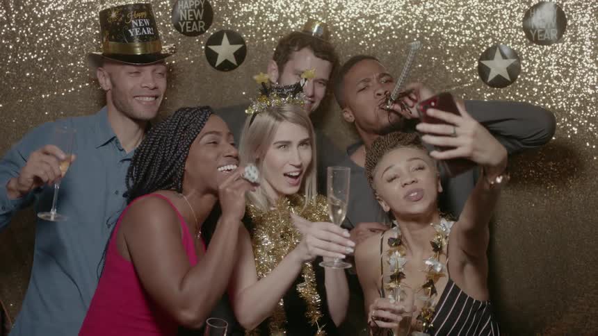 A group of people with new years decorations on are taking a selfie together