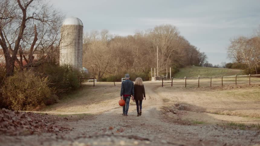 A man and woman carry pumpkins