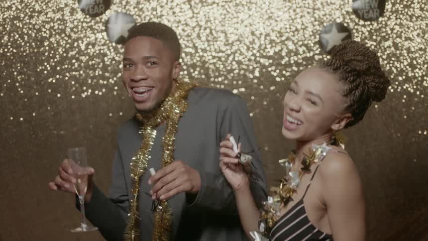 A man and woman dance while drinking champagne at a party