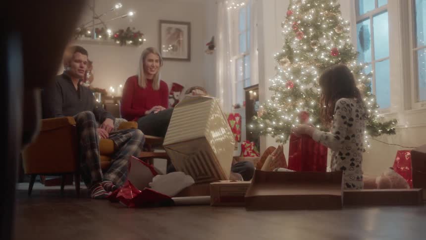 A family opens gifts next to a christmas tree