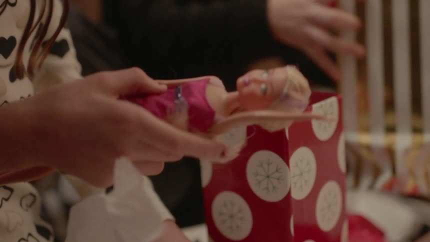 A girl unwraps a barbie on christmas
