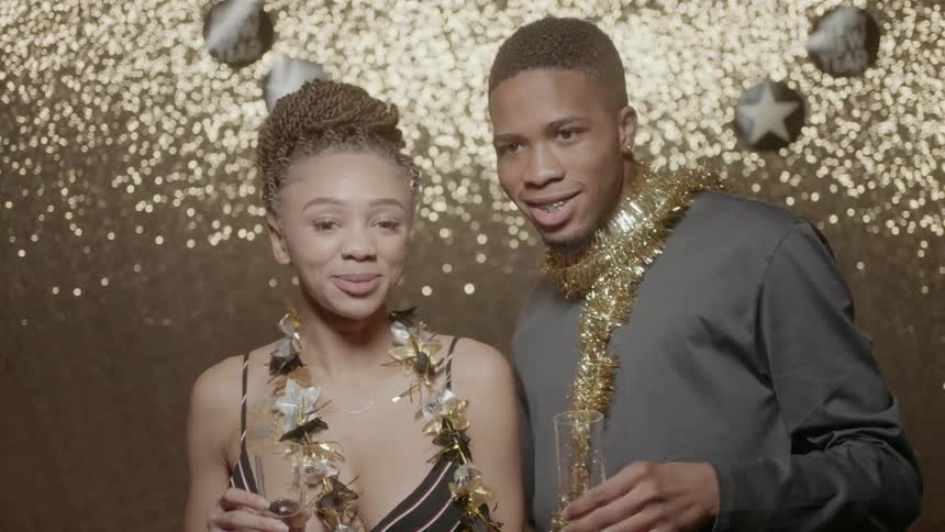 A couple raise their champagne glasses in a toast at new years