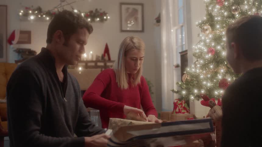 A family opens gifts next to a christmas tree