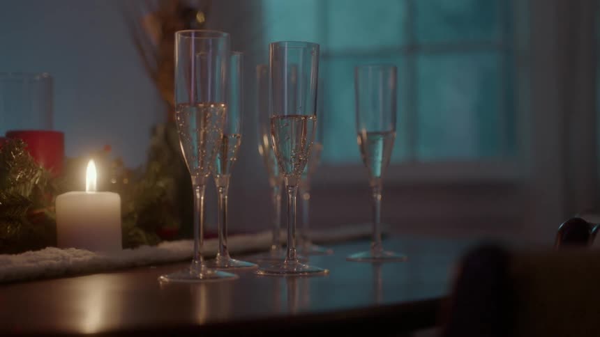 Glasses of champagne sit next to christmas decorations on a table