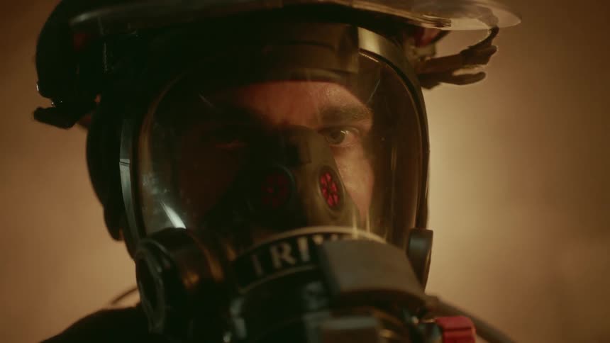 Fireman looking at flames as they reflect off his face shield