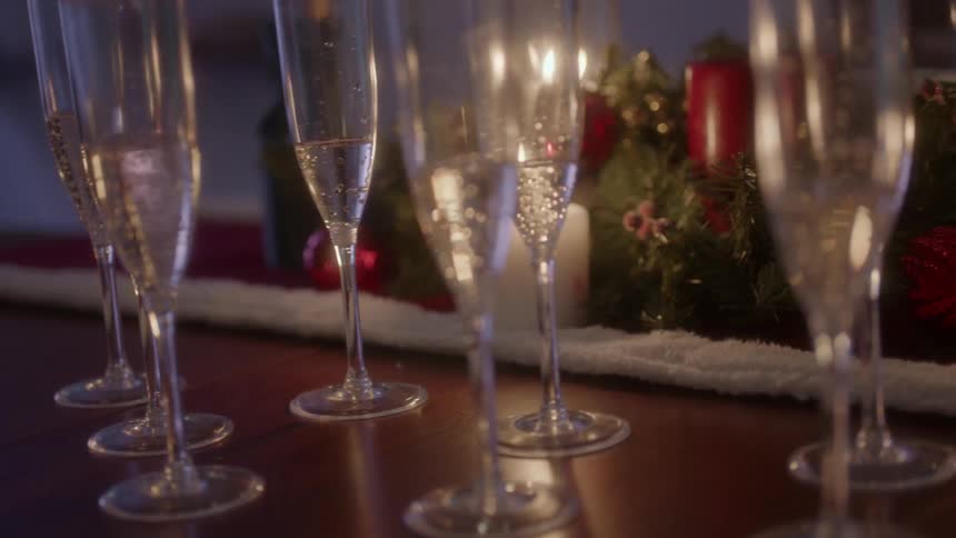 Champagne flutes sit on a table as candle light flickers