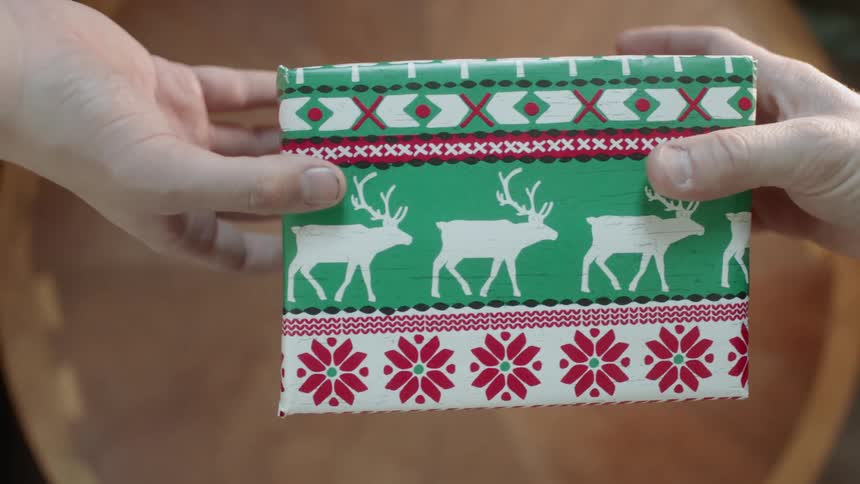 A christmas present is exchanged over a wood table
