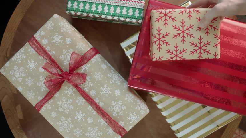 Hands place wrapped christmas gifts on a table top