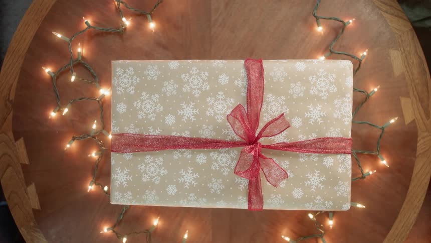 A christmas present is exchanged over a wood table