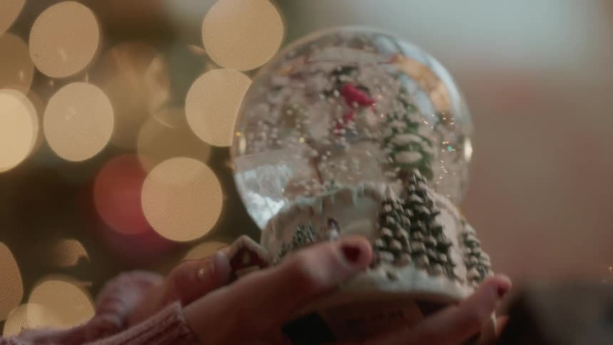 A girl shakes a snow globe and then puts it down