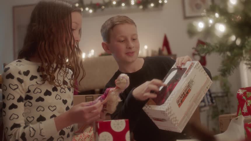 A brother and sister smile as they look at their christmas presents