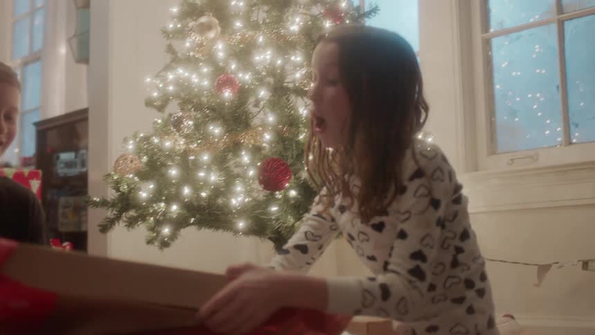 Boy and girl unwrap christmas present