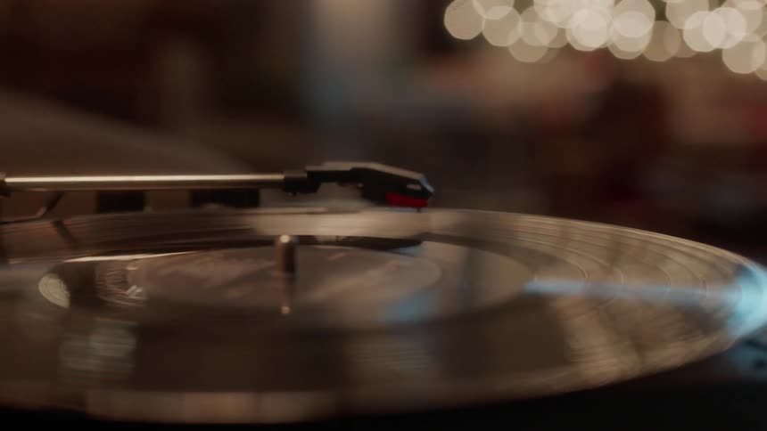 An album spins on a record player next to a christmas tree