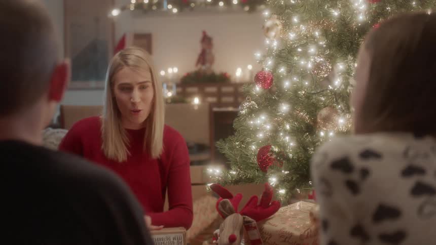 A family opens gifts next to a christmas tree