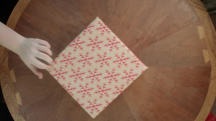 Person reaches for and slides a present across a table