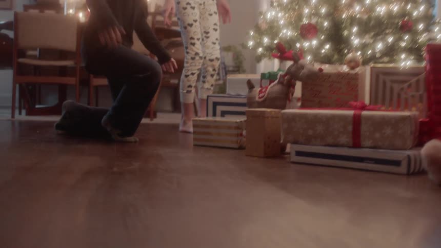 A boy and girl run to a christmas tree