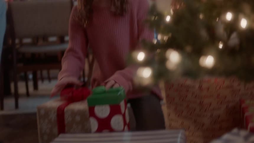 A girl and boy look at presents next to a christmas tree
