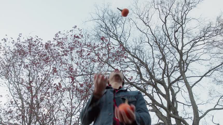 Man juggles three small pumpkins
