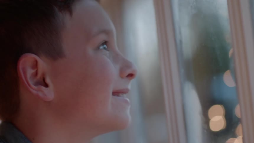 A boy looks out a window on christmas